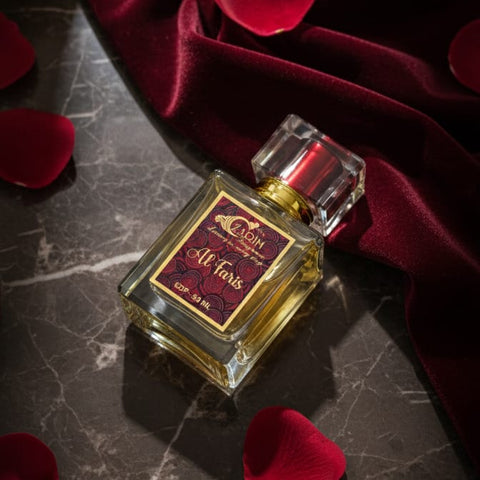 Perfume bottle with 'Al Fardis' label on a dark surface with red fabric and petals.