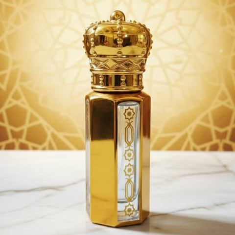 Gold perfume bottle with intricate design on a marble surface and patterned wall background